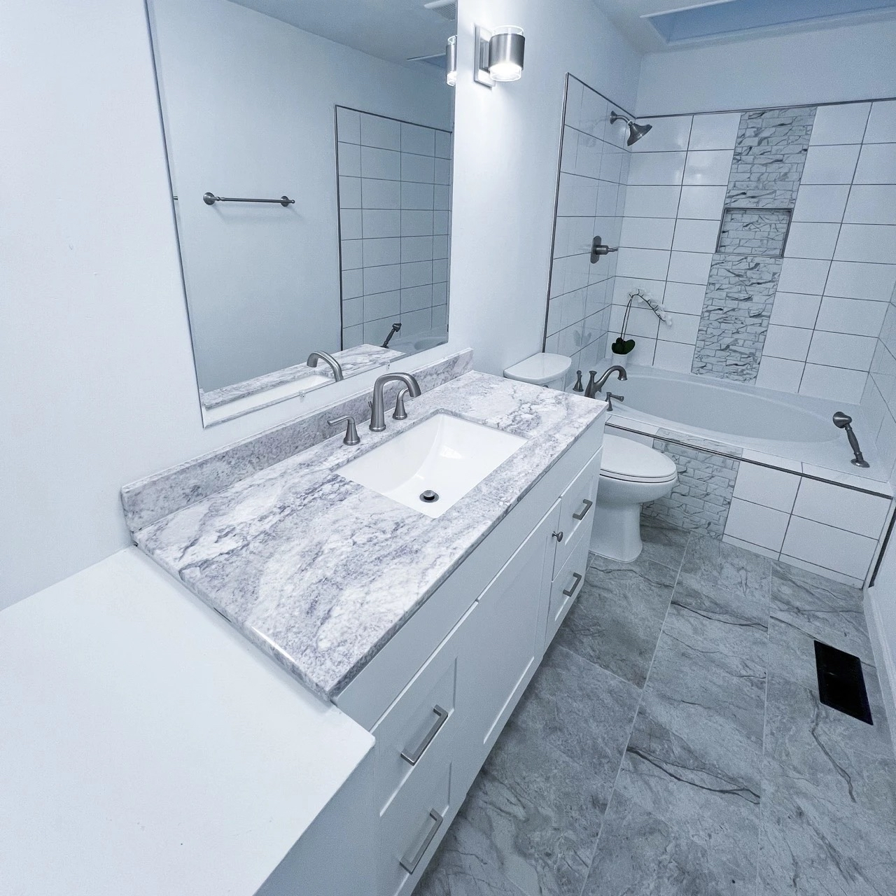 Marble vanity and tiled bathtub